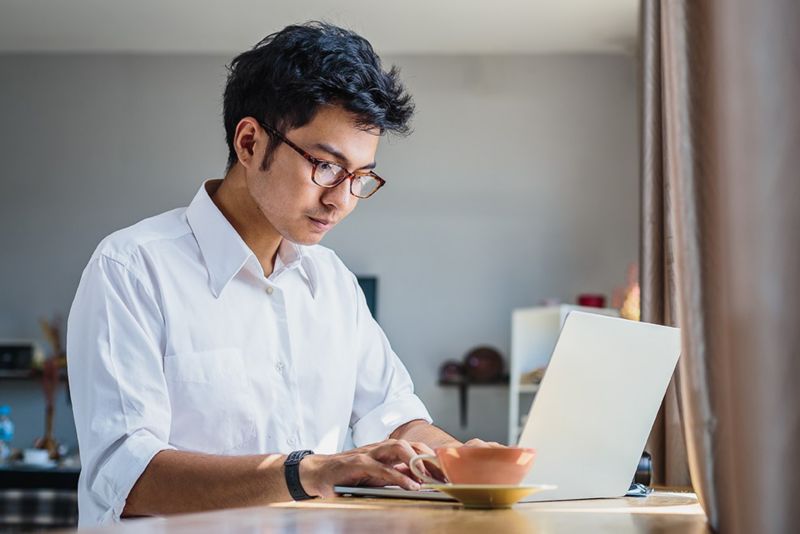 Young Asian business man working with laptop computer while sitting in coffee shop cafe