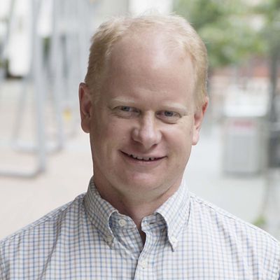 Profile photo of Mark Easton smiling towards the camera against an out of focus background of a RMIT campus