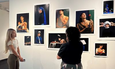 Two women stand in front of a wall of photography prints. Works by Yueran Li, photo by Pia Johnson.