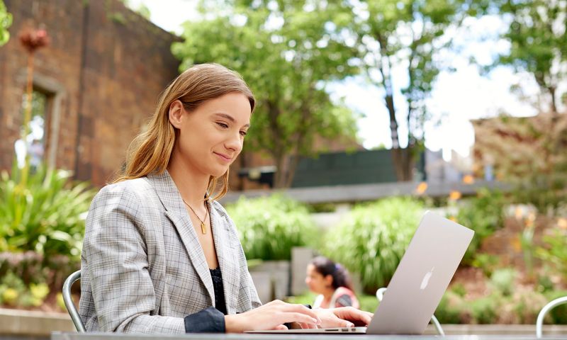 RMIT Student working on laptop outside on campus