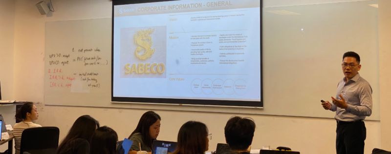 Photo of a lecturer teaching in front of a white board showing the general corporate information of Sabeco to a group of postgraduate students