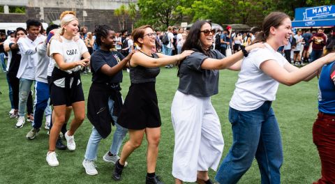 Students laugh in a conga line at an event.