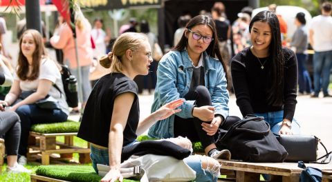 Students sit on the ground and chat at the City Campus.