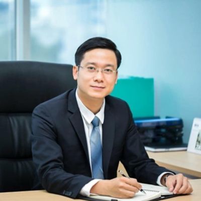 an asian man in suit sitting at a desk 