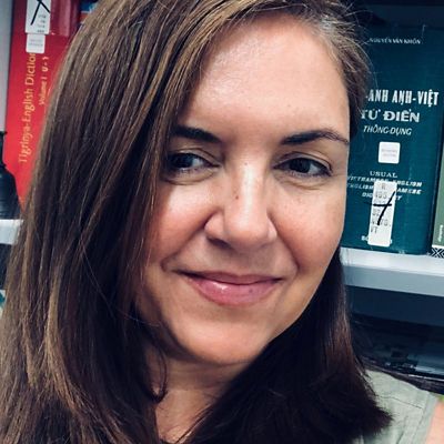 Profile photo of Olga García-Caro. Photo is close up with Olga smiling slighty off from where the camera is. Books on bookshelves in the background.