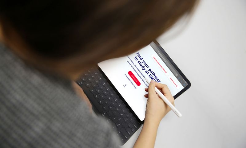 Female student holding stylus to use on laptop while browsing the pathways finder tool.