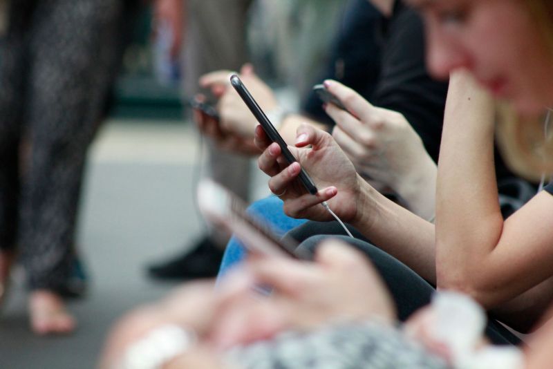 Photo of a group of people sitting down, looking and using their mobile phones.