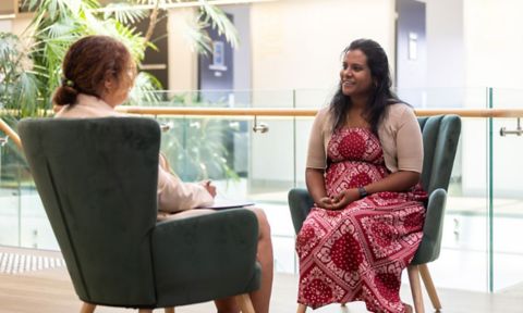 Two women sitting in lounge chairs chatting