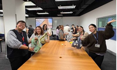 Group of people gathered around a conference table smiling and posing for a photo.