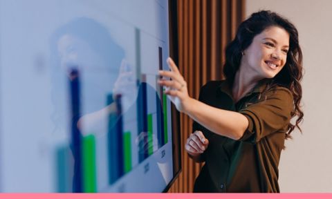 Student pointing at an interactive whiteboard during an engaging office presentation, showcasing positive results while smiling confidently and inspiring her colleagues