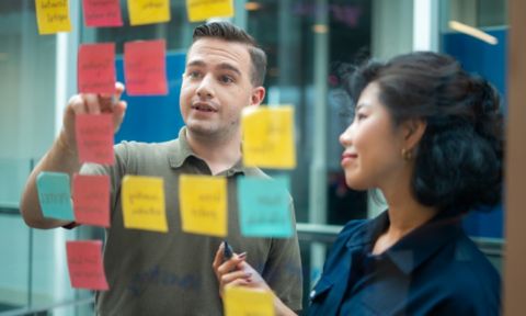 Two RMIT postgraduate students writing sticky notes and working on a collaborative project