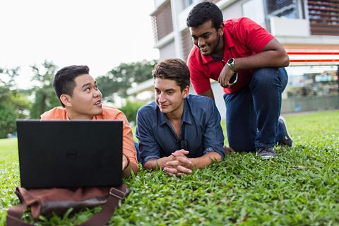 A group of international students discussing while lying on the grass