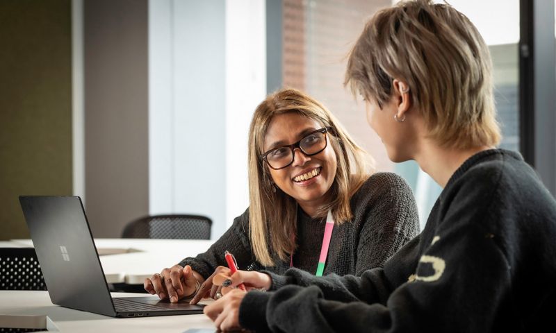 Anne maree with a students at table in discussion.