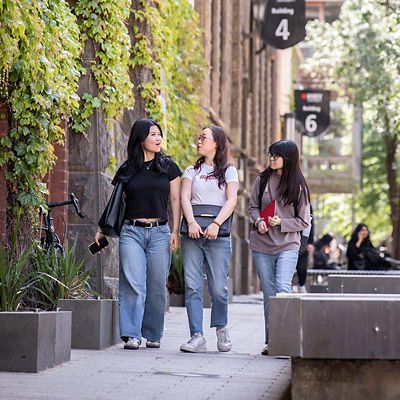 Three students walk and chat on bowen steet.