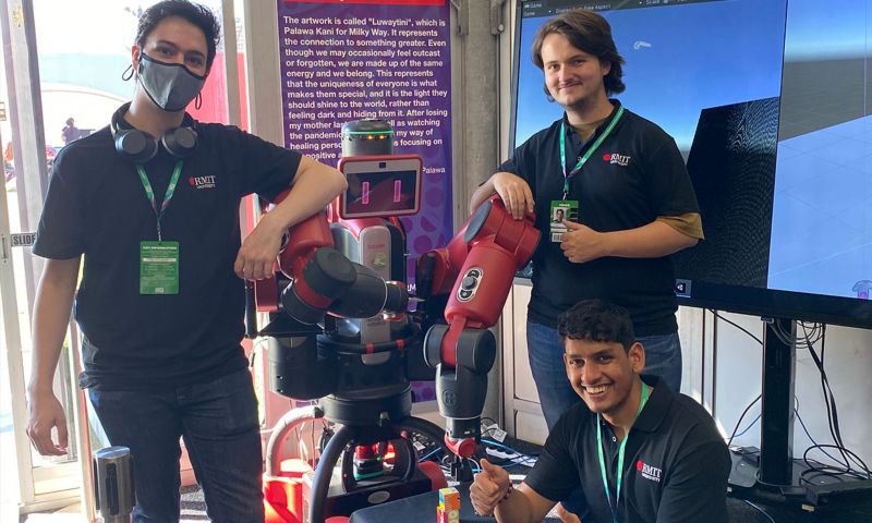 Three people standing around a red and black virtual reality robot