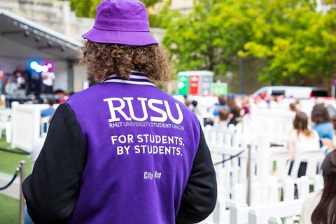 A student wears a purple hoodie with RUSU branding.