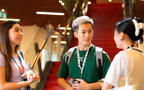 three students having a discussion in a lobby area