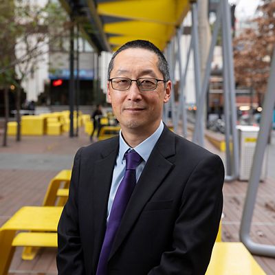 a headshot of an asian man in suit smiling 