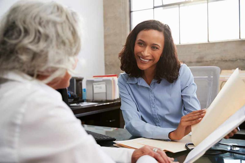 Smiling female analyst in consultation with senior woman