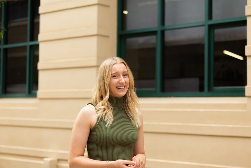 Ellen is pictured standing in front of RMIT's building 3 smiling.