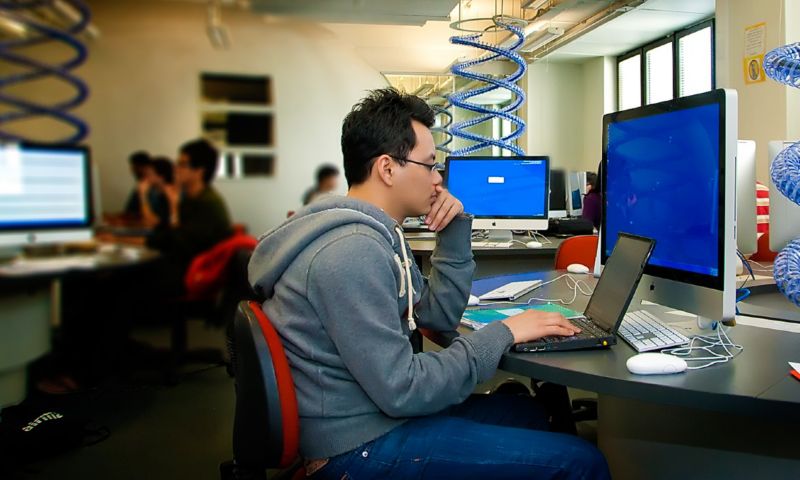 Student sitting in front of computer screens in a computer science lab