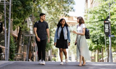 Three students walking and talking on Bowen St, City campus