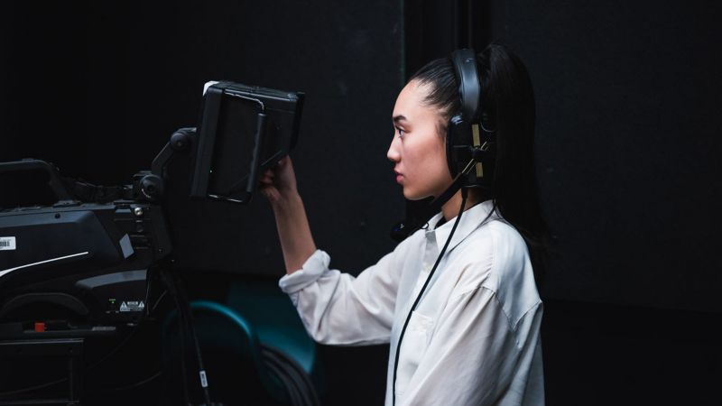 Female student wearing headphones and using camera equipment