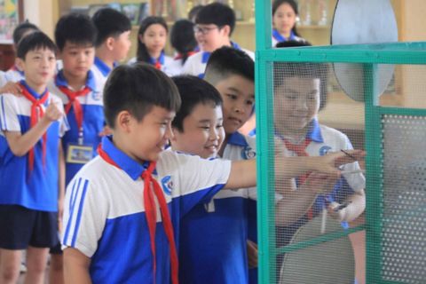 students-in-uniform-closely-examining-a-display-or-experiment-behind-a-mesh-panel.jpg