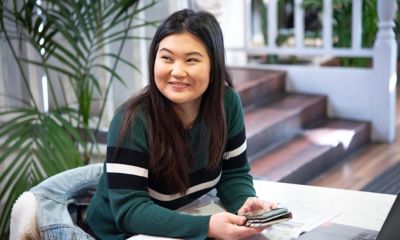 Tanya Setyawan - RMIT Bachelor of Communications student, smiling, sitting at a table holding a mobile phone 