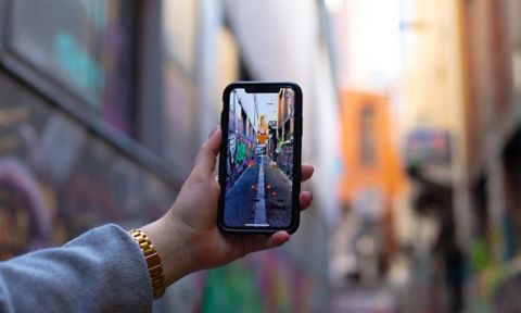 Person holding their phone taking a photo of a laneway