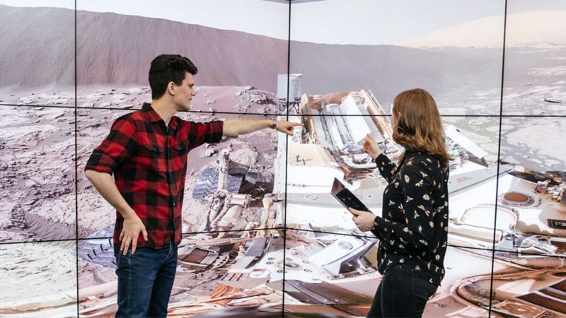 A male and female student in front of a screen in the VX lab