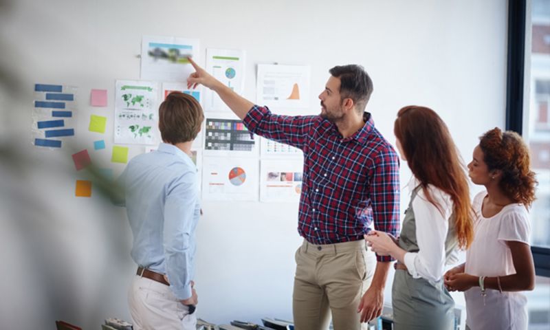 Business people readingt diagrams on office wall