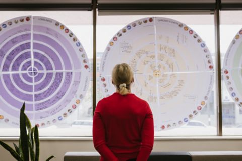 A woman standing and looking at charts on a window.