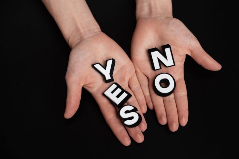 Một tay cầm chữ YES, một tay cầm chữ NO