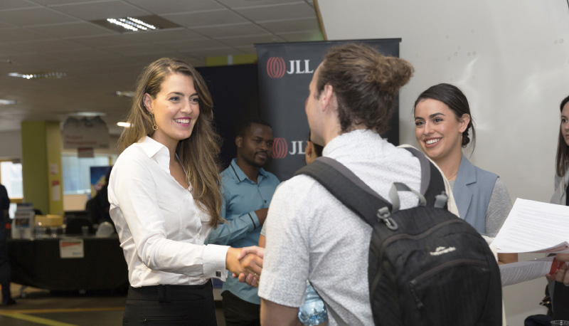 Woman in industry meeting student at jobs fair.