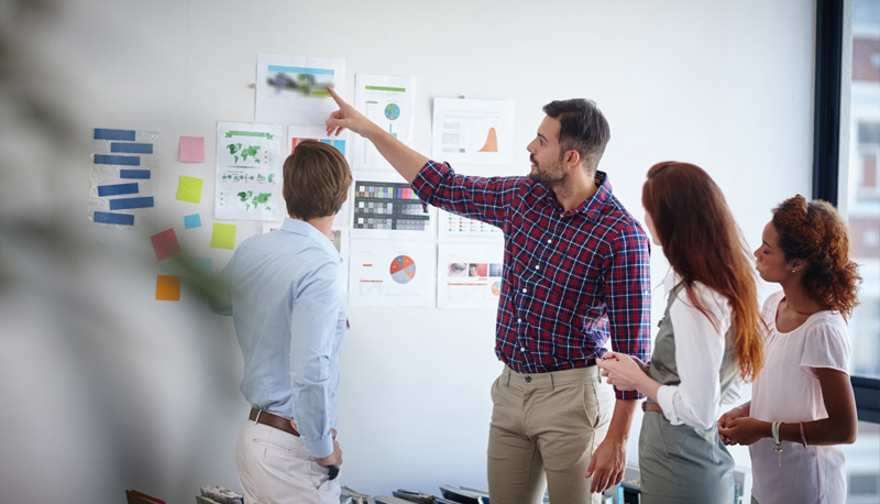 A group of people planning a project with information on the wall