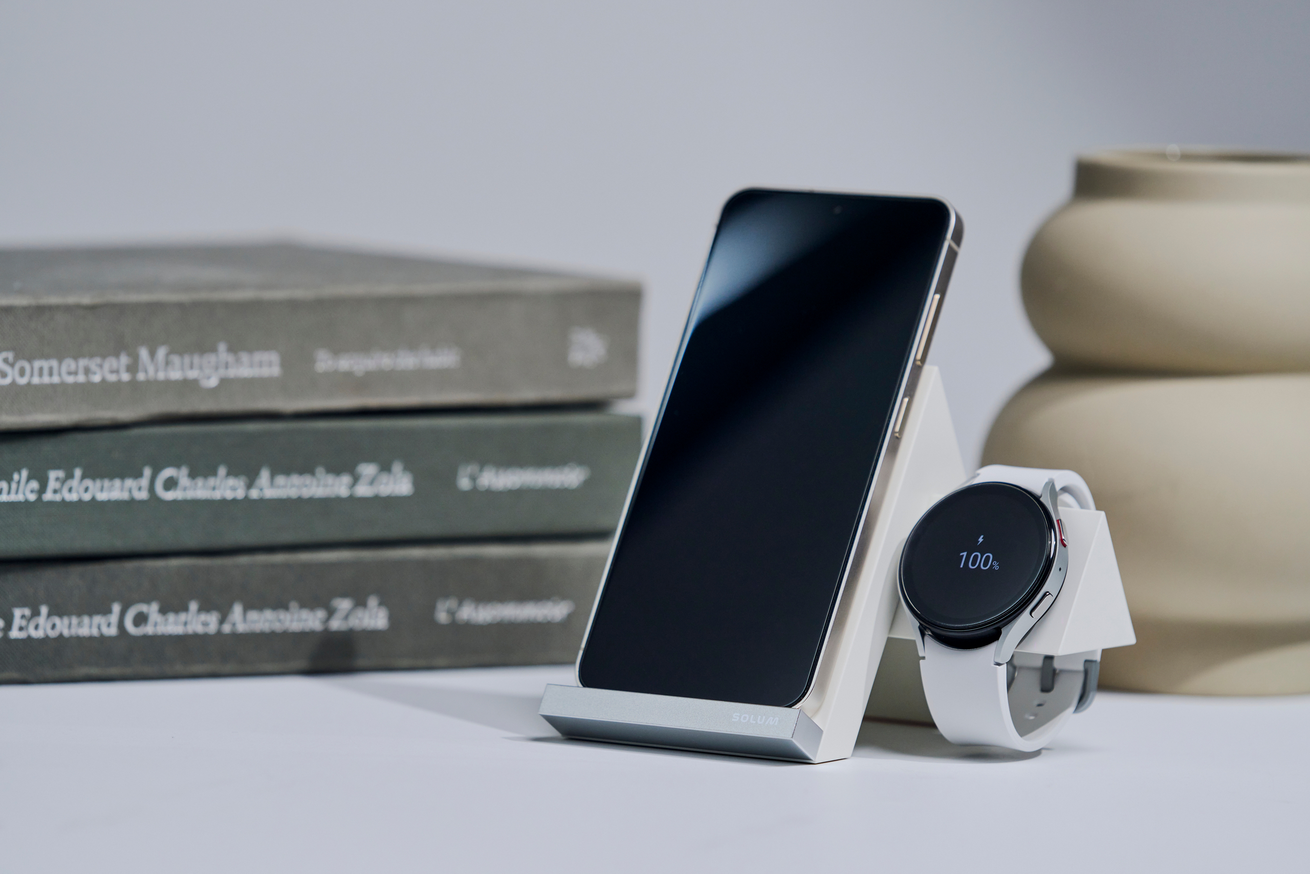 Smartphone and smartwatch placed on a white dual wireless charging stand.