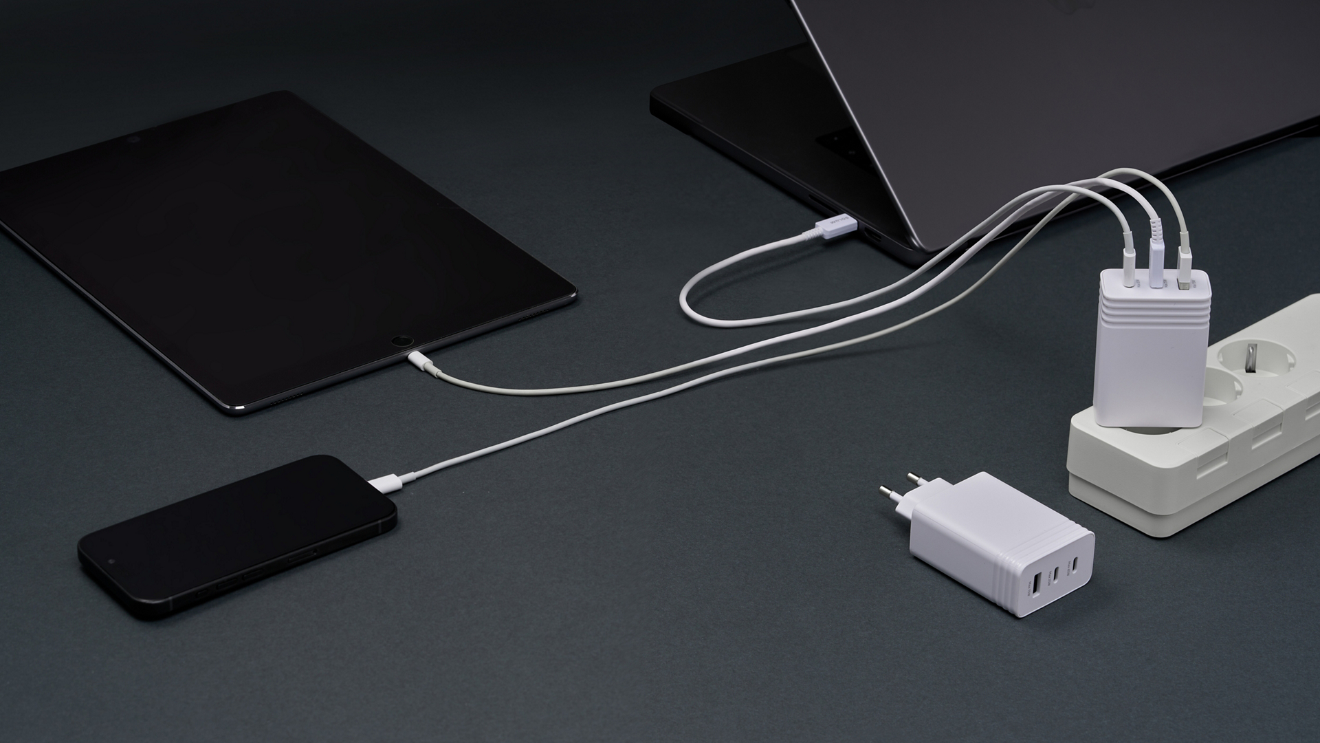Three devices charging from one wall-mounted multi-port charger.