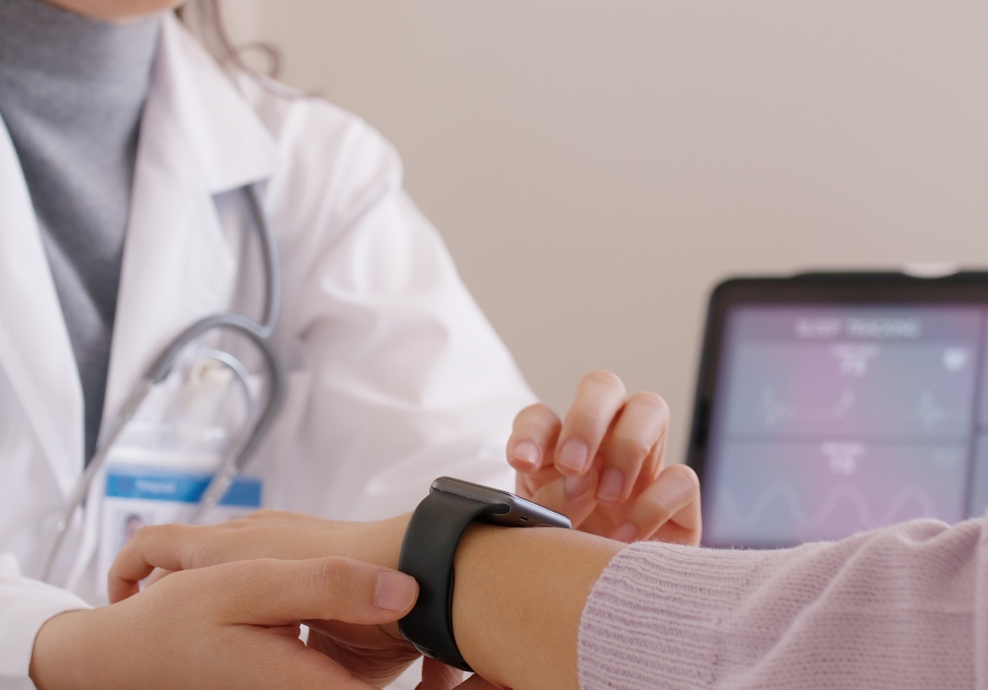 Doctor diagnosing woman wearing smartwatch with temp sensor.