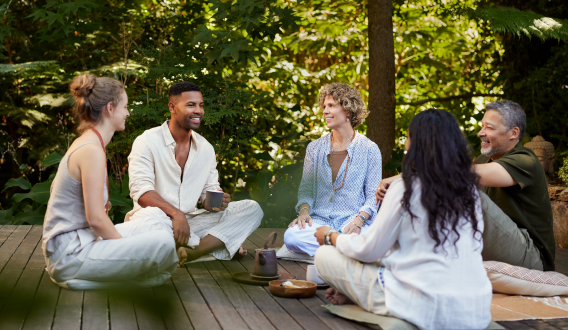 A group of people sitting together in a relaxed office setting, participating in a wellness session.