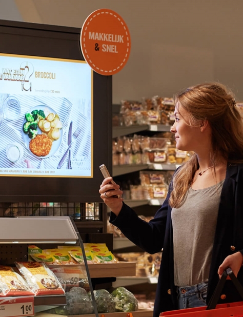 Shopper scans a digital recipe screen in a grocery store