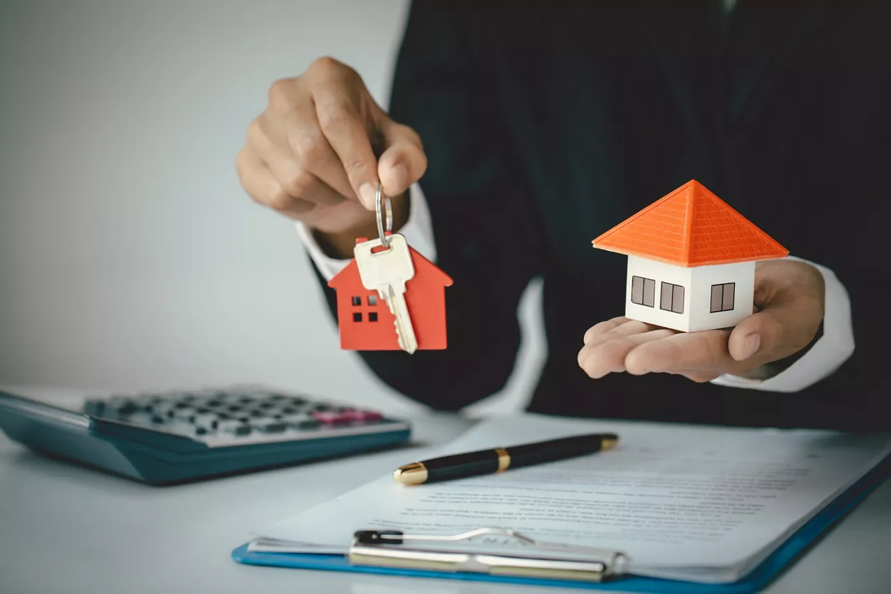 Your new house, woman hands holding a  model house and key. Mortgage property insurance dream moving home and real estate concept