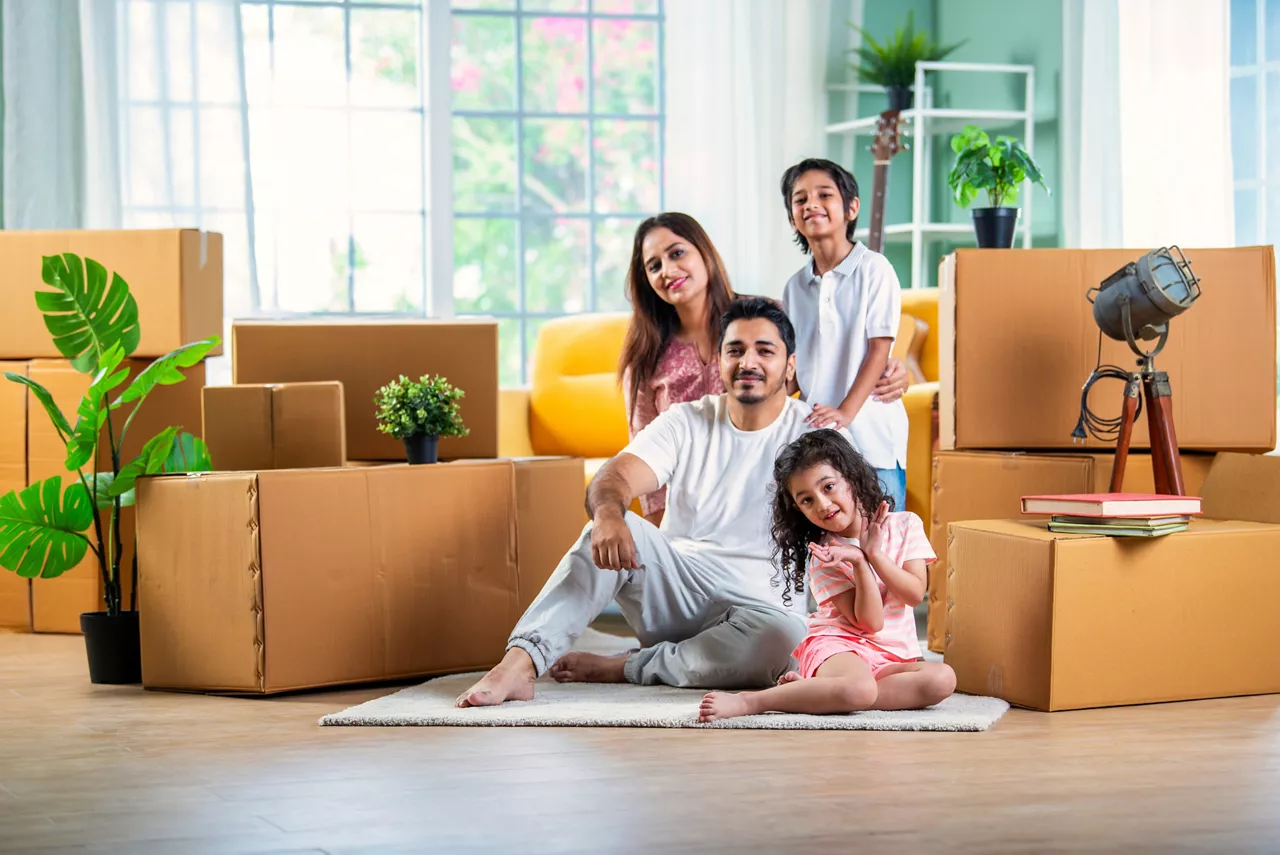 House move concept. Happy Indian young family sitting on the floor in new home