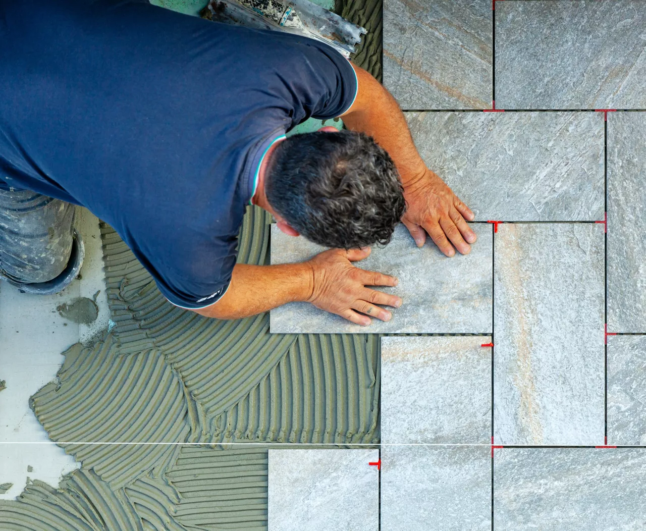 Tiler carefully lays every single tile with the help of a wire to respect the geometry of the flooring.