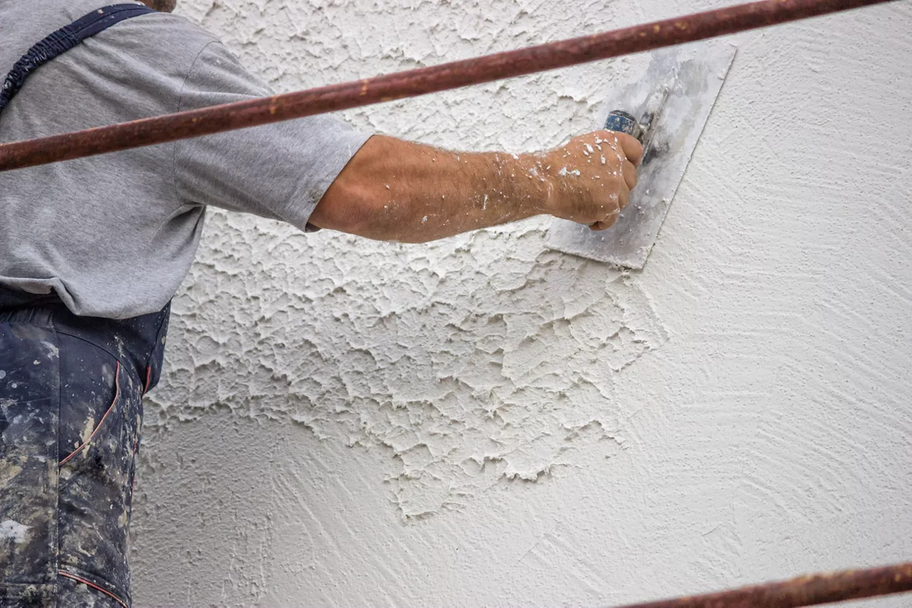 Decorative plaster applied on the surface by a steel trowel. White cement based decorative top coat plaster resistant on outside whether conditions. Selective focus.
