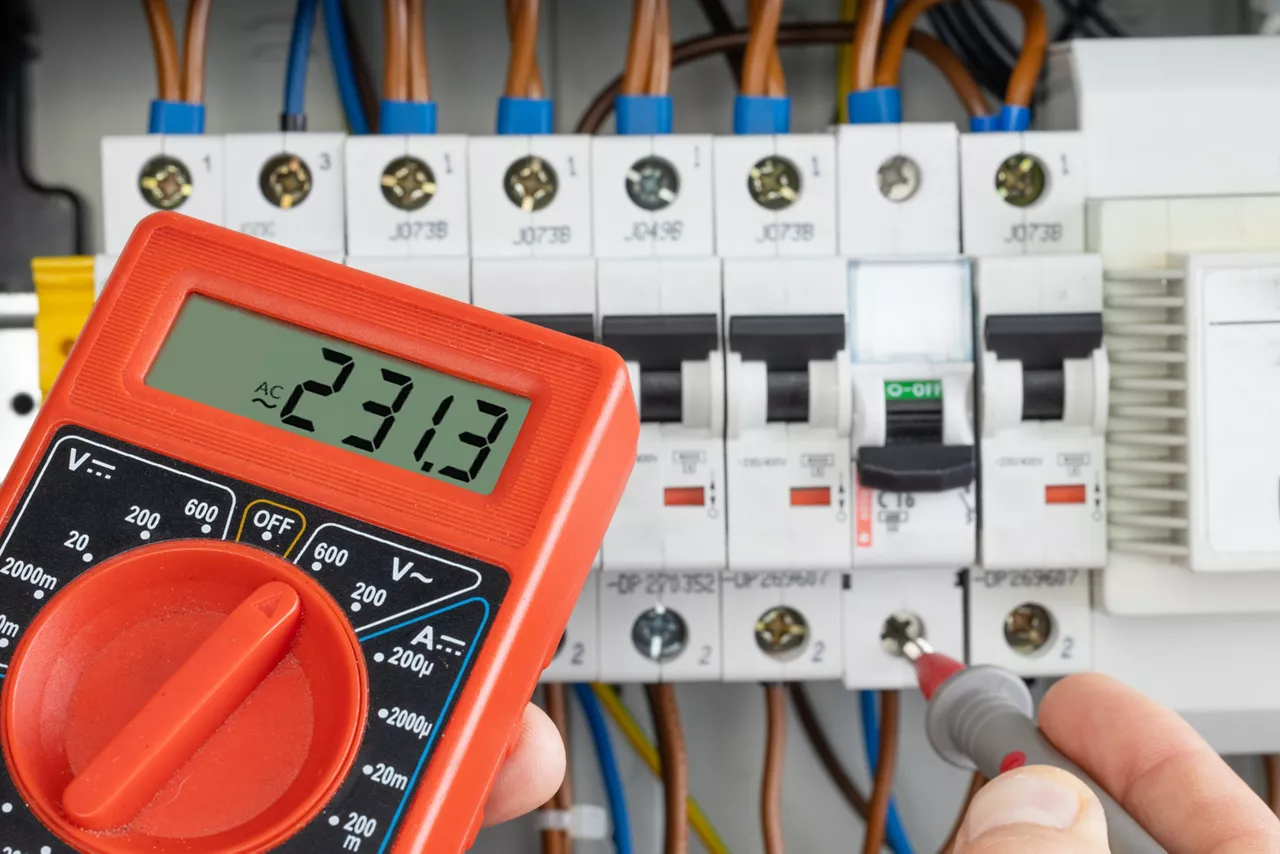 Hand Testing Electrical Circuit with Multimeter