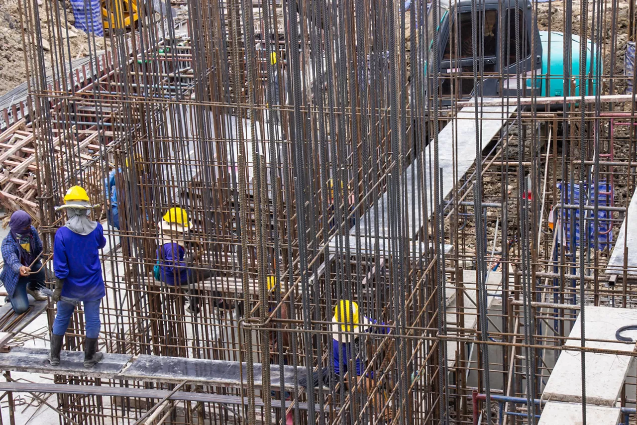 Construction workers fabricating large steel bar reinforcement bar at the in construction area building site.