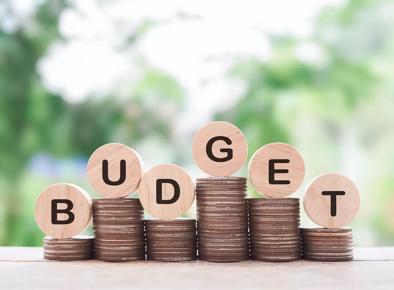 Wooden blocks with the word BUDGET on stack of coins. The concept about budget planning and allocation