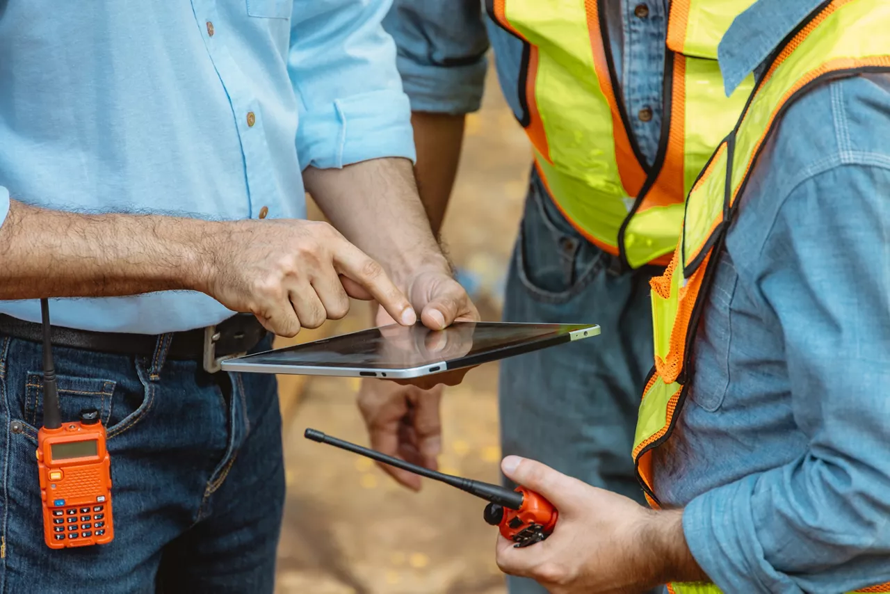 Professional construction engineer workers team working cooperate together consulting looking at tablet screen at project building construction site.