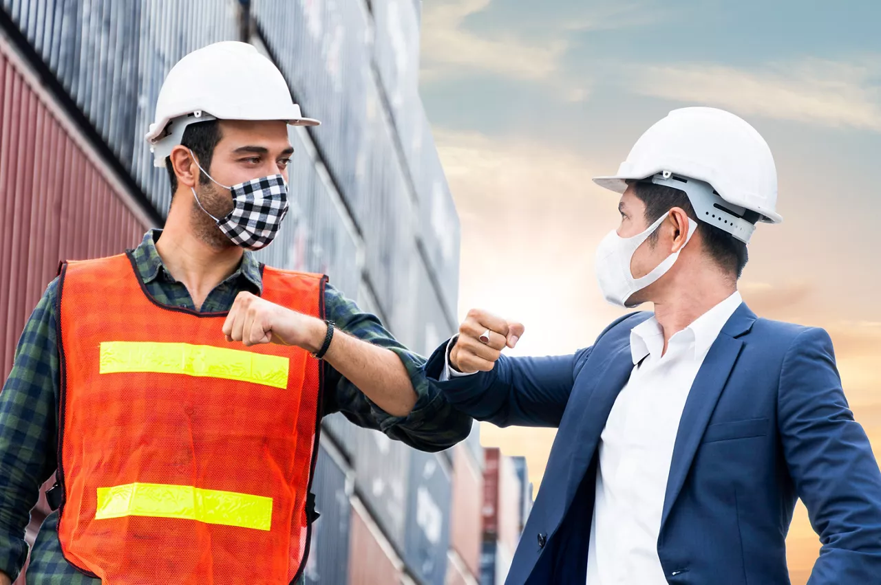 construction site worker and foreman wearing hygiene face mask elbow bump greeting in New Normal adaptation to prevent Coronavirus or Covid-19 spreading. social distance working style at warehouse